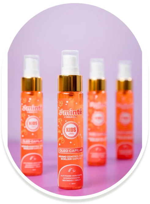 Botellas de aceite capilar Minte Kids naranja sobre mesa rosa