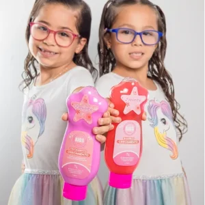 Dos niñas con vestidos de unicornio sosteniendo shampoo y tratamiento Minte Kids rosa
