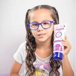 Niña con gafas azules mostrando crema para peinar Minte Kids