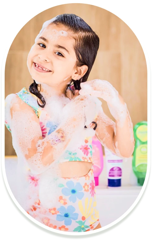 Niña con traje de baño de flores lavando su cabello con shampoo infantil Minté y mucha espuma